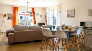 Ein modernes Wohnzimmer mit einer Couch, einem Esstisch, Stühlen und einer Küchenzeile mit einer Mikrowelle.