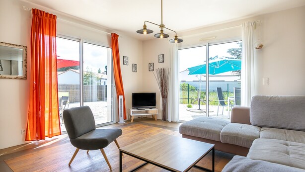Ein Wohnzimmer mit Sofa, Sessel, Fernseher und Tisch.
