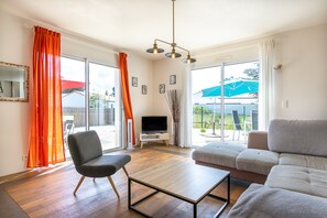 A living room with a sofa, a chair, a TV, and a table.