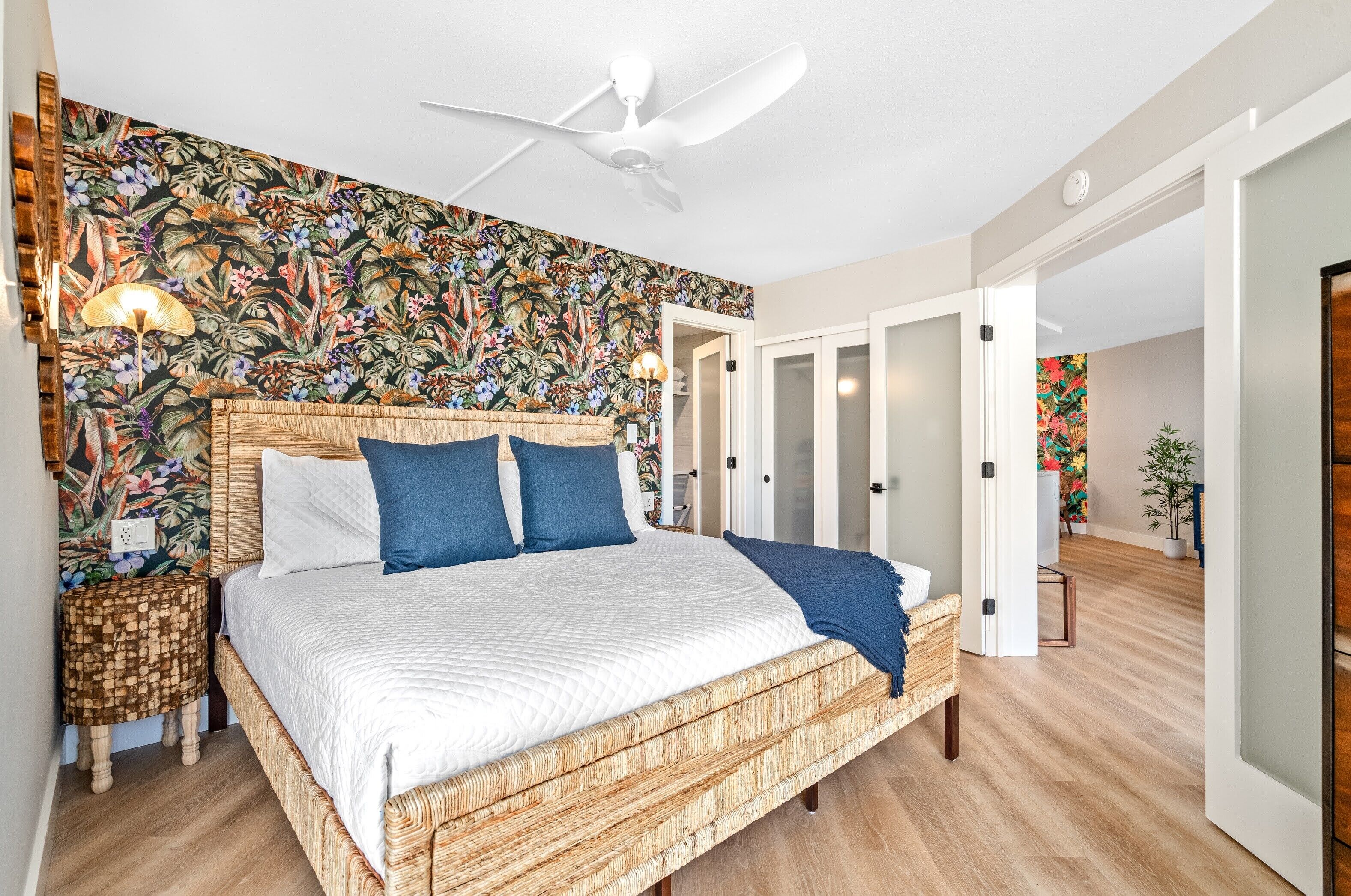 Ein Schlafzimmer mit einem großen Bett, einem Deckenventilator und blumigem Wandpapier.