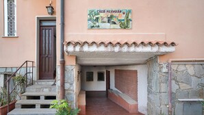 A building entrance with a stone staircase, a door, a tiled roof, and a sign above. - Apartment 'Casa Di Lo' with Private Terrace and Wi-Fi (Laigueglia)