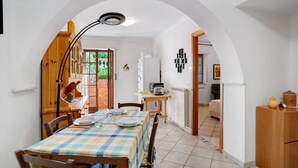 A dining area with a checkered tablecloth, wooden chairs, a lamp, and a view through an archway to a kitchen and living area. - Apartment 'Casa Di Lo' with Private Terrace and Wi-Fi (Laigueglia)