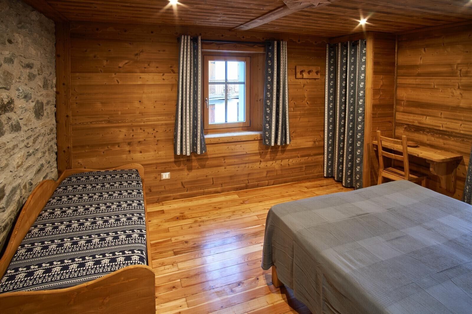 Une chambre dans un chalet en bois, avec deux lits, une fenêtre et des rideaux.