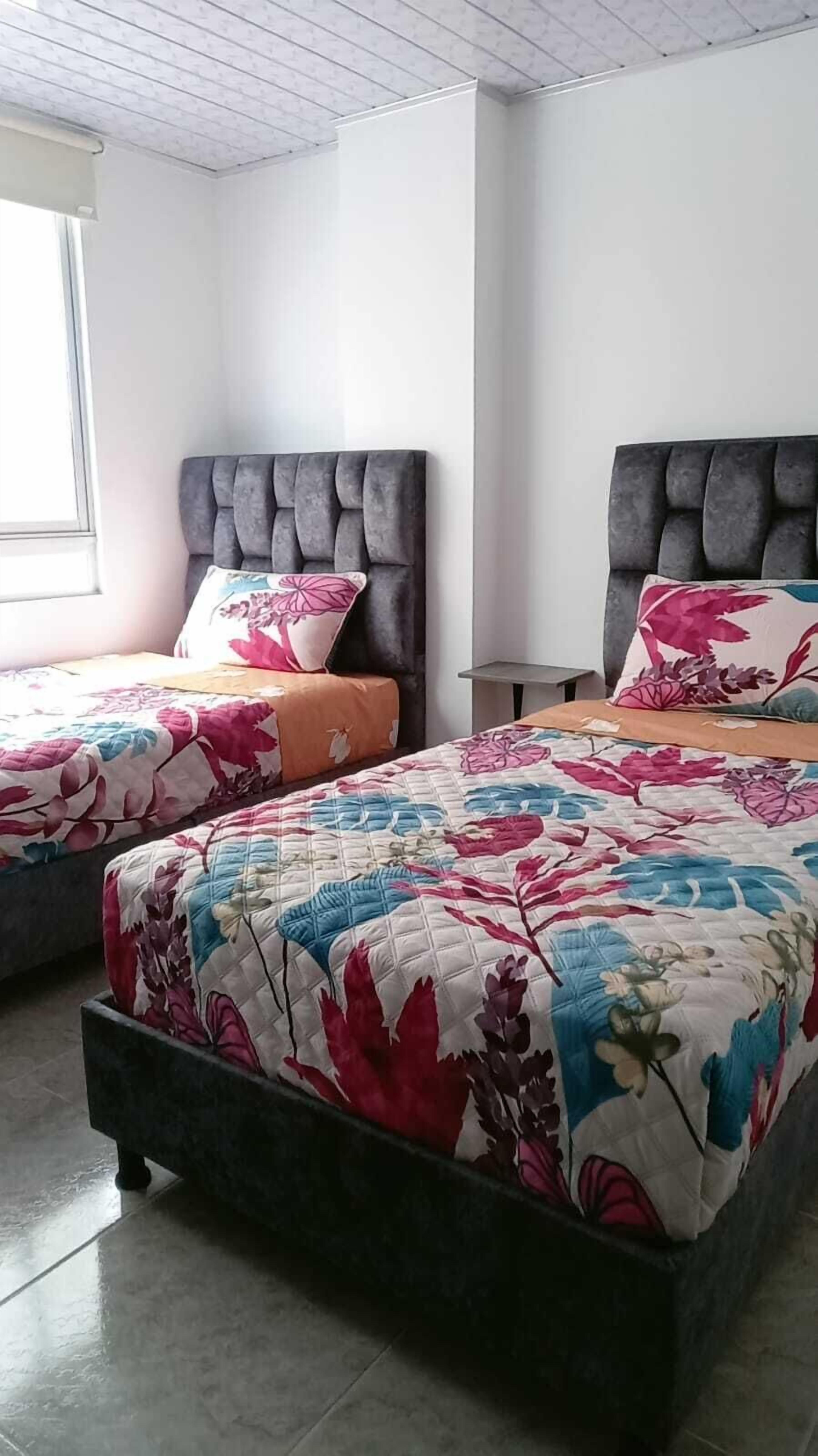 A bedroom with two beds, each with a floral bedspread and a headboard.