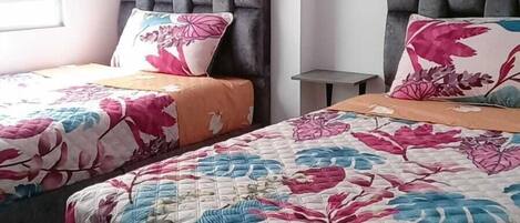 A bedroom with two beds, each with a floral bedspread and a headboard.