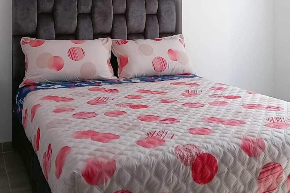 Un dormitorio con cama, cabecera y techo estampado.