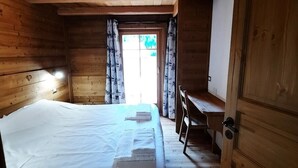 Une chambre dans une cabane en bois, avec un lit, un bureau et une porte.