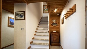 Un escalier avec des marches en bois et une porte en bois ornée d’un emblème circulaire.