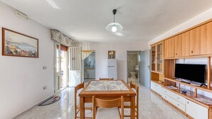 A spacious kitchen with a dining table, chairs, a TV, and cabinets. - Apartment 'Villino Scapucci' with Sea View, Private Terrace and Air Conditioning (Santa Maria di Leuca)