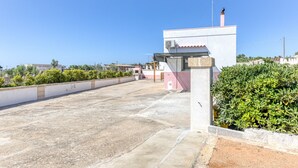 A rooftop terrace with a concrete floor, a small building with a chimney, and a hedge. - Apartment 'Villino Scapucci' with Sea View, Private Terrace and Air Conditioning (Santa Maria di Leuca)