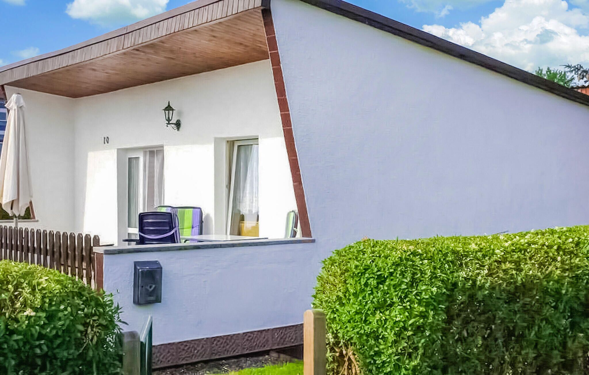 Un bâtiment blanc avec un toit en pente, un petit porche et une boîte aux lettres.