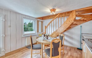 Ein Essbereich mit einer Holztreppe, einem runden Tisch mit Stühlen und Blick durch ein Fenster.