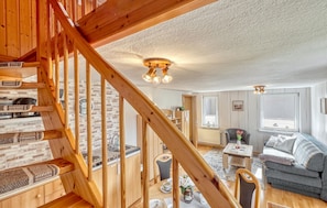 A wooden staircase leading to a living area with a sofa, a table, and a chair.