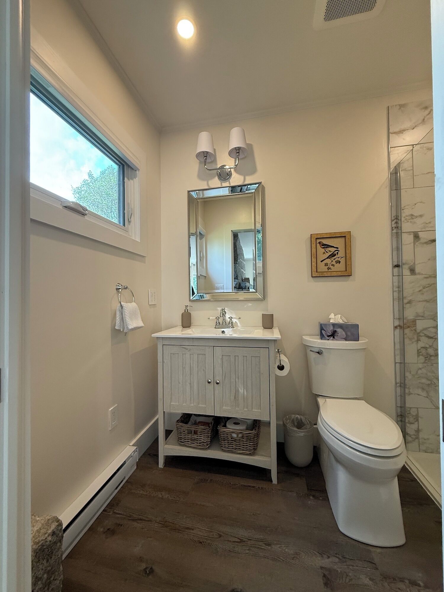 A bathroom with a white vanity, a large mirror, a toilet, and a shower.