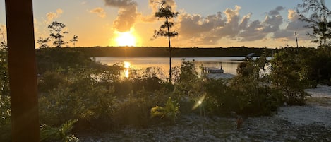 A sunset over a lake with trees and a dock.