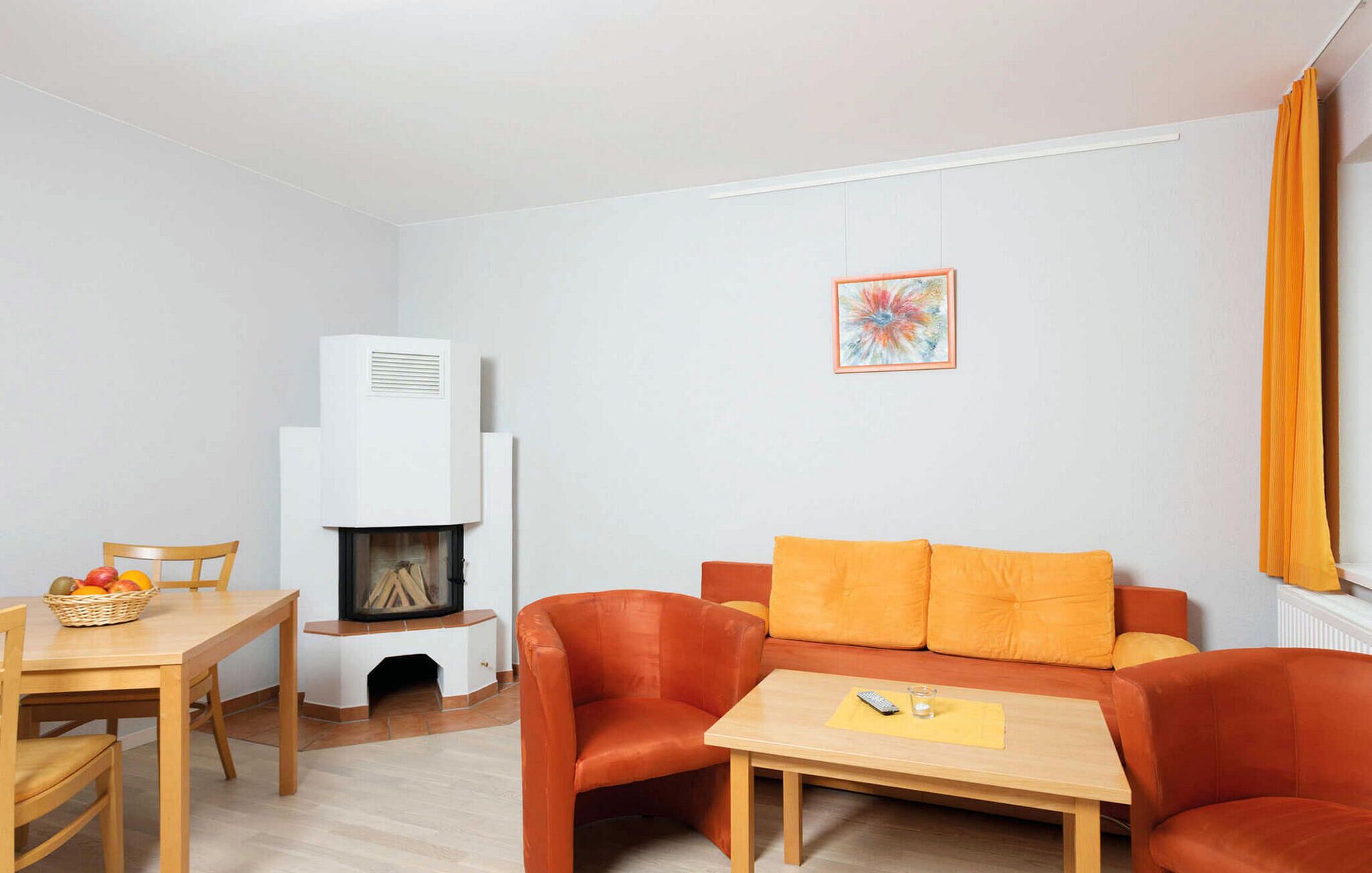 Ein Wohnzimmer mit Kamin, einem orangefarbenen Sofa, einem Holztisch und einem gerahmten Bild an der Wand.