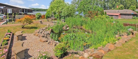 A garden with a pond, stone benches, and a wooden structure.