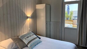 Une chambre à coucher avec un lit, des oreillers, une armoire et une fenêtre avec des rideaux.