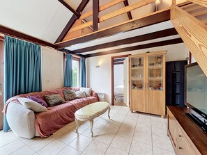 Une pièce confortable avec un canapé, une petite table, un meuble avec des portes en verre et un téléviseur.
