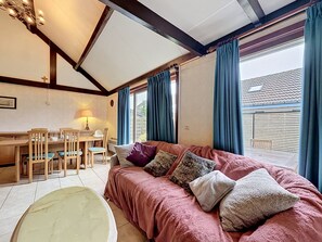 Une piÚce confortable avec un canapé, une table à manger, des chaises et une lampe.
