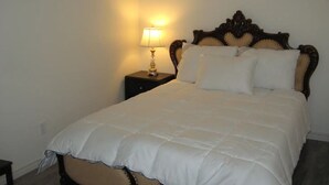 A neatly made bed with a white duvet, a wooden headboard, and a bedside table with a lamp. - Beautiful 2-bedroom Guest Home in Guelph (Guelph)