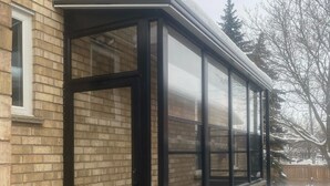 A corner window with a black frame, brick wall, and a snow-covered ground. - Beautiful 2-bedroom Guest Home in Guelph (Guelph)