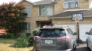 A residential house with a garage door, a basketball hoop, and a parked SUV. - Beautiful 2-bedroom Guest Home in Guelph (Guelph)