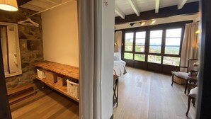 Une pièce avec un mur en pierre, un banc en bois et un lit donnant sur l’extérieur.