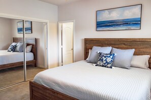 A bedroom with a wooden headboard, a large mirror, and a painting of the ocean.