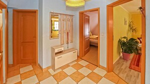 A hallway with a checkered floor, wooden doors, a mirror, and a hanging light fixture. - Ferienwohnung Waren (Müritz) (Waren (Müritz))