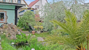 A garden with a pond, various plants, and a white fence. - Ferienwohnung Waren (Müritz) (Waren (Müritz))
