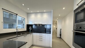 Une cuisine moderne avec des meubles blancs, un plan de travail noir et des appareils électroménagers intégrés.