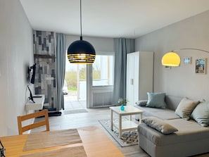 Un salon moderne avec un canapé, une petite table et un luminaire suspendu.