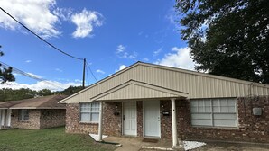 A single-story brick house with a gabled roof and a front porch.