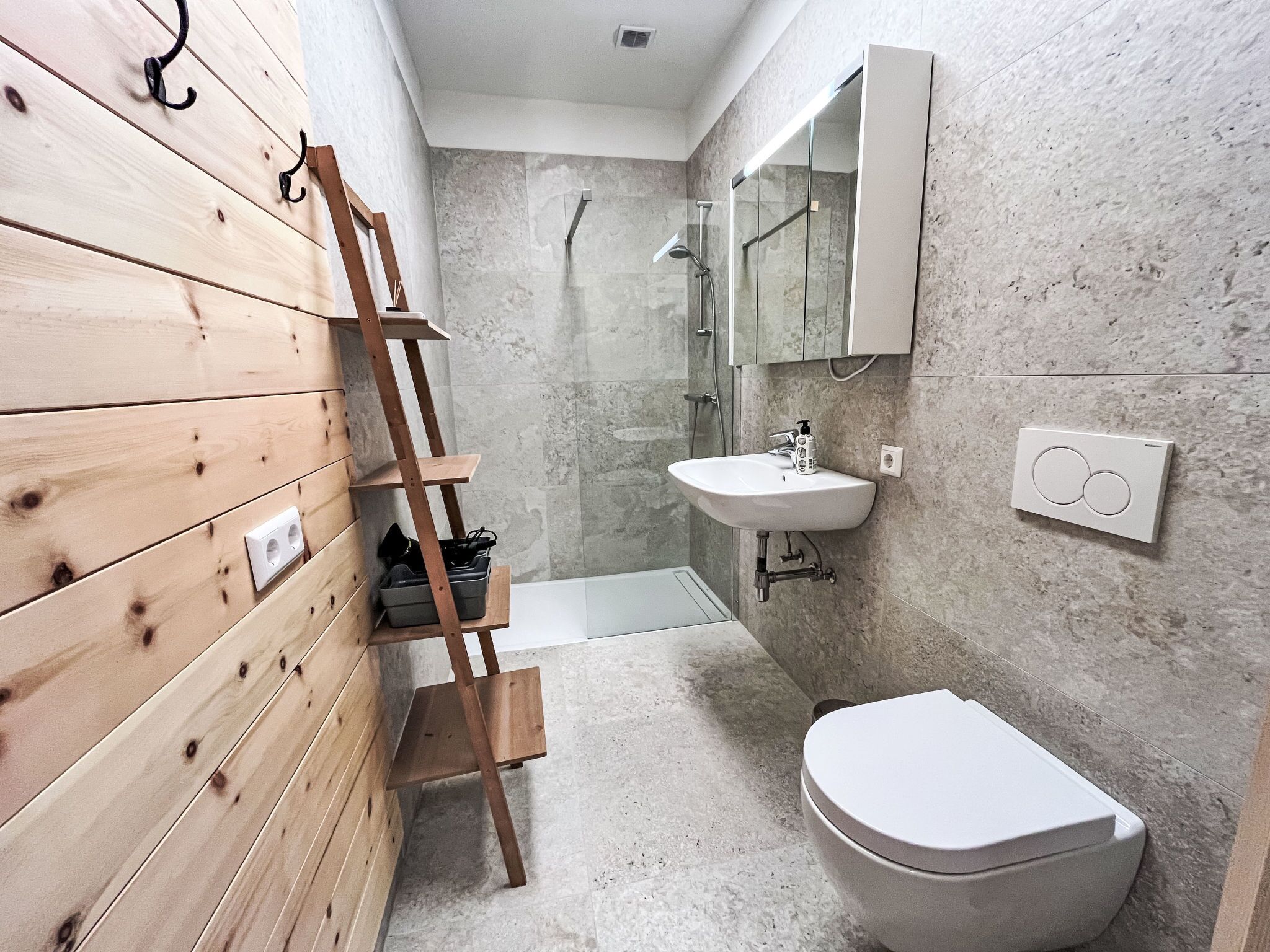 A modern bathroom with a wooden vanity, a shower, a sink, and a toilet.