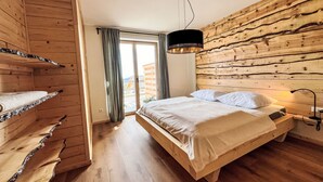 Una habitación de madera con una cama, un lámpara colgante y vistas al exterior.