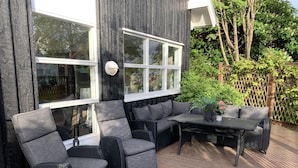 An outdoor patio with wicker furniture, including a sofa and a table, and large windows. - 4 Bed House Sleeps 8 -Car, Barbecue, Balcony (Reykjavik)