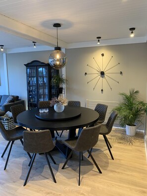Een moderne eetruimte met een ronde tafel, donkere stoelen en een hanglamp.