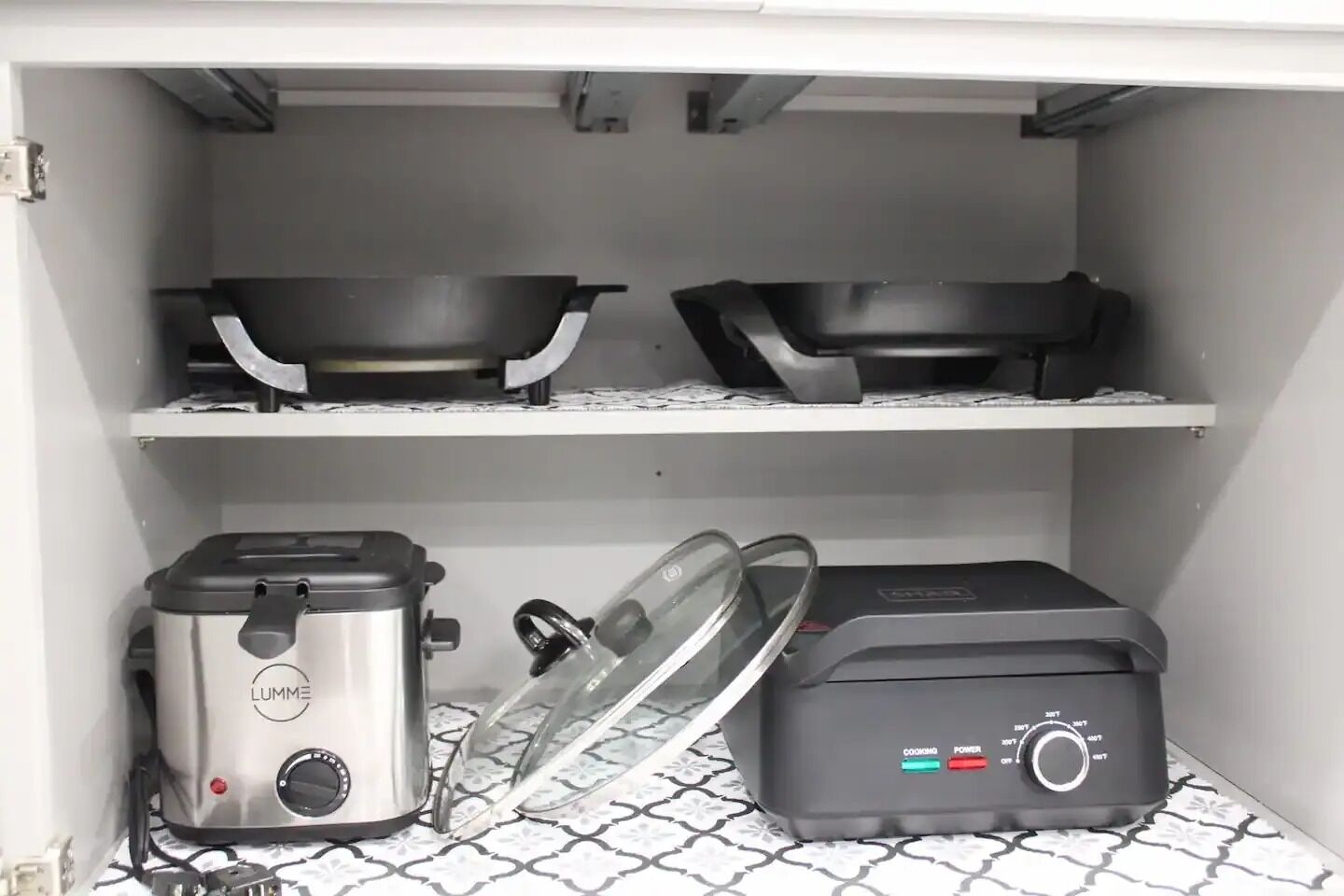 Een keuken met een LUMME rijstkoker, een zwart apparaat met een bedieningspaneel, en twee zwarte kommen op een plank.