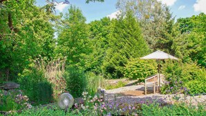 A garden with a wooden bench, a stone pathway, and a metal sculpture. - Ferienwohnung Rheinsberg (Rheinsberg OT Linow)