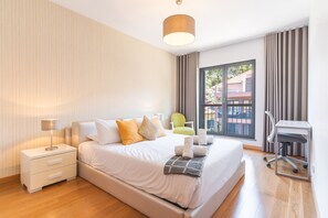 Een moderne hotelkamer met een groot bed, een bureau, een stoel en uitzicht.