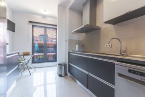 A modern kitchen with a dishwasher, a stainless steel sink, and a window overlooking a residential area.