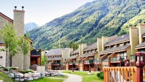 Une rangée d’immeubles modernes à plusieurs étages, dotés de balcons, se dressant sur fond de montagnes verdoyantes.