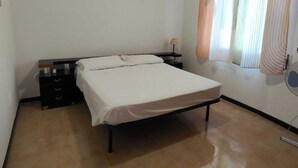 Ein Schlafzimmer mit einem Bett, einem Nachttisch, einem Deckenventilator und einem Fenster mit Vorhängen.