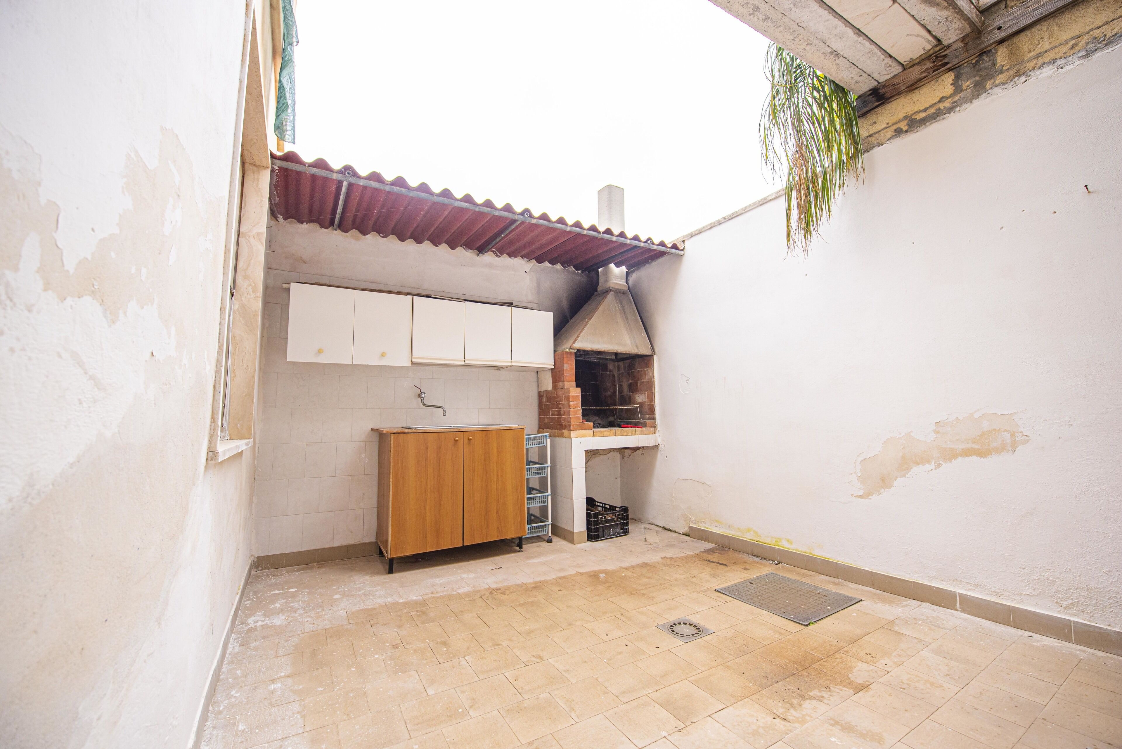 Un petit espace cuisine fermé, doté d’un sol carrelé, d’un meuble en bois et d’un four en briques.