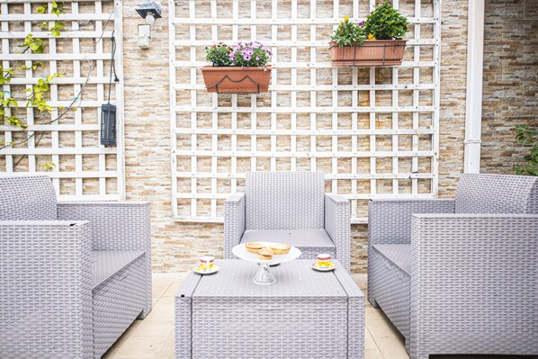 An outdoor seating area with wicker furniture and a table set for a meal.