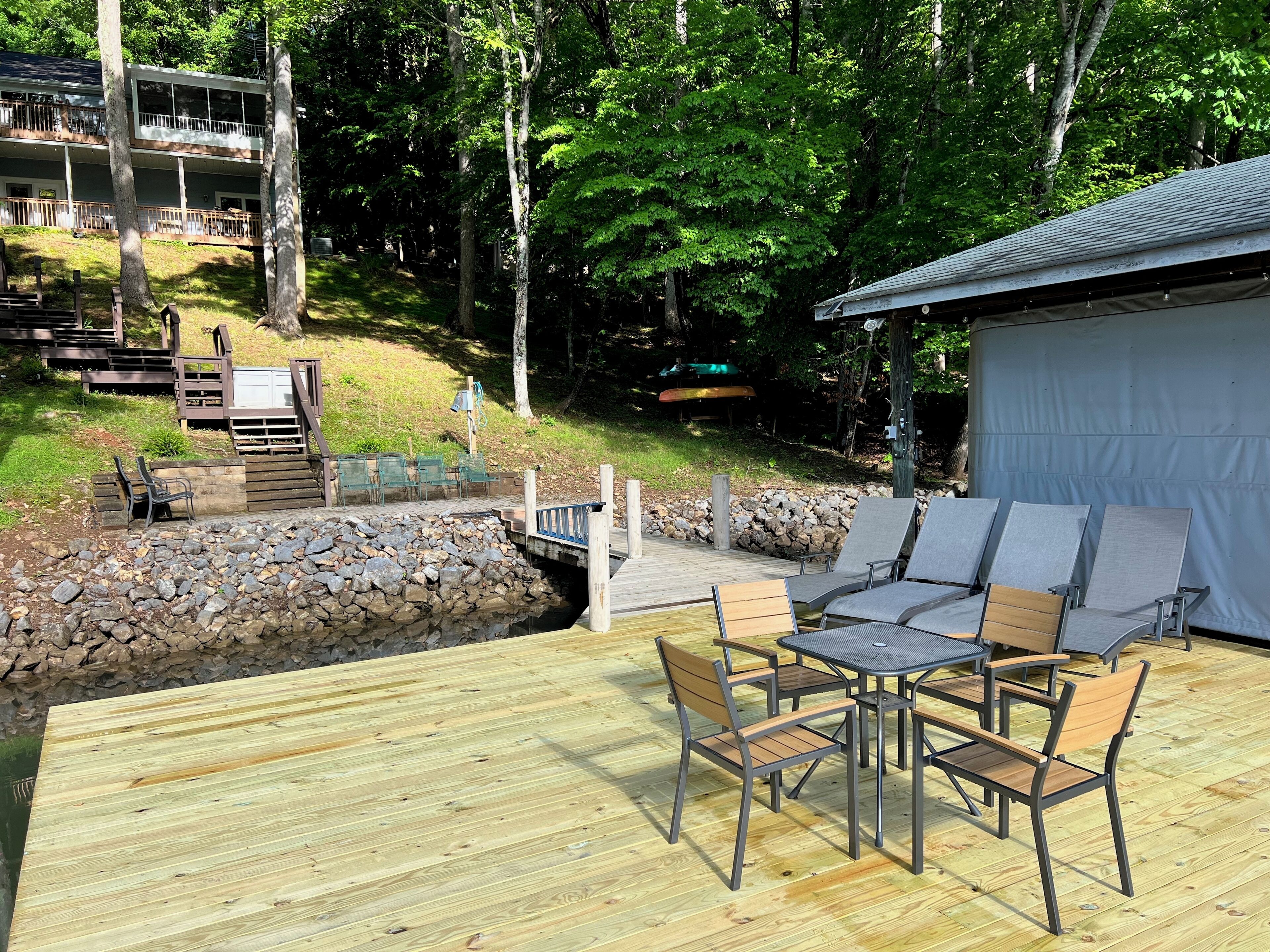 A wooden deck with outdoor furniture, a stone wall, and a building with a covered area.