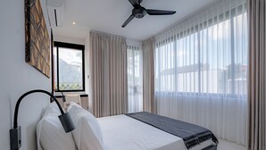A modern hotel room with a bed, a ceiling fan, and large windows with sheer curtains. - Town House Camy Bali (Bali)