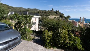A coastal view with a white building, a car, and a church with two towers. - Garden an Seaview by Interhome (Laigueglia)