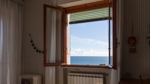 A bedroom with a large window, a radiator, a bedside table, and a small cabinet. - Garden an Seaview by Interhome (Laigueglia)